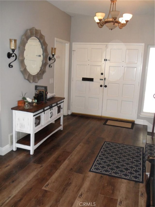 entryway featuring a chandelier, dark wood-type flooring, and baseboards