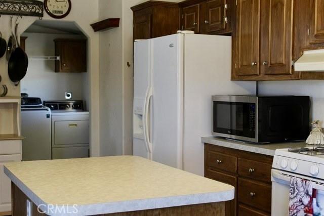 36072 Meadow Grove Rd, Yermo, CA 92398 - kitchen with white appliances, separate washer and dryer, under cabinet range hood, light countertops, and a center island
