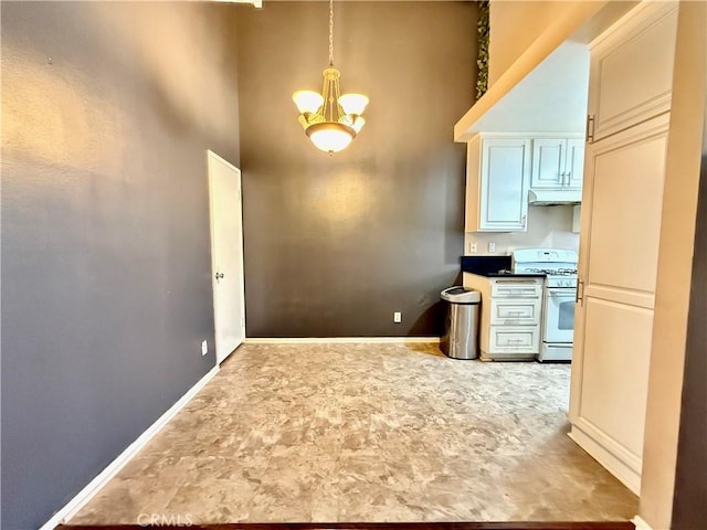 18122 Sundowner Way Unit 1108, Canyon Country, CA 91387 - kitchen featuring white range with gas cooktop, a chandelier, under cabinet range hood, baseboards, and a towering ceiling