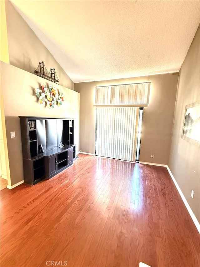 18122 Sundowner Way Unit 1108, Canyon Country, CA 91387 - unfurnished living room featuring wood finished floors, vaulted ceiling, baseboards, and a textured ceiling