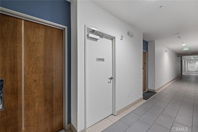 hallway with tile patterned floors and baseboards