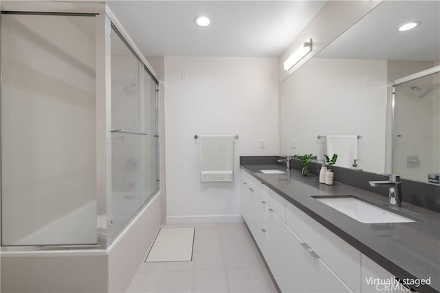 bathroom featuring tile patterned flooring, recessed lighting, double vanity, baseboards, and enclosed tub / shower combo