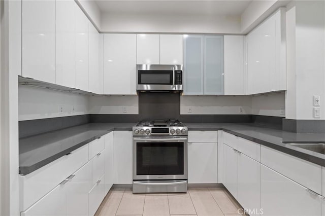 kitchen with stainless steel appliances, white cabinets, dark countertops, and modern cabinets