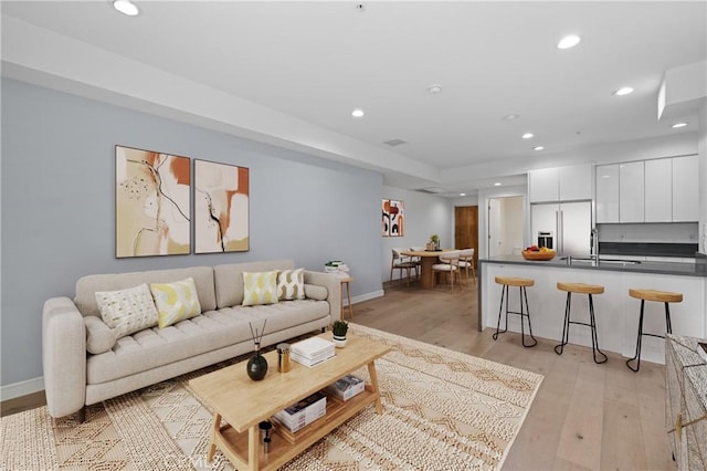 living room with recessed lighting, light wood-style flooring, and baseboards