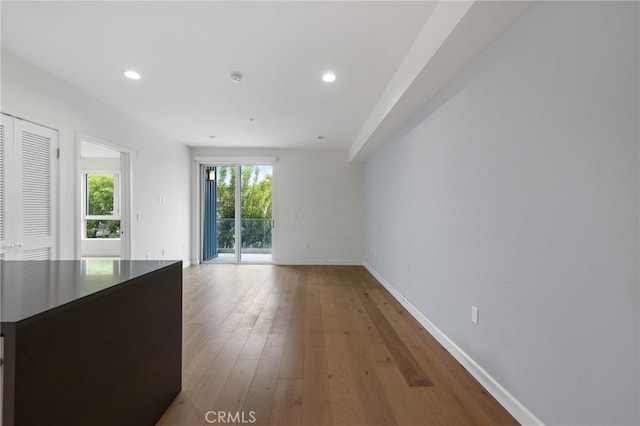 unfurnished dining area with baseboards, hardwood / wood-style flooring, and recessed lighting