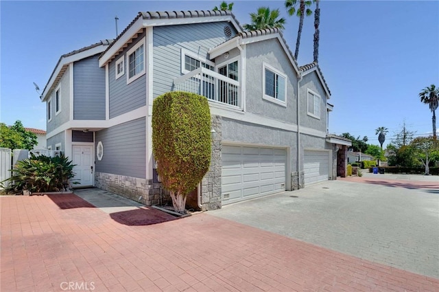 2461 Oneida St Unit B, Pasadena, CA 91107 - view of front of home featuring a garage, stone siding, driveway, a tiled roof, and a balcony