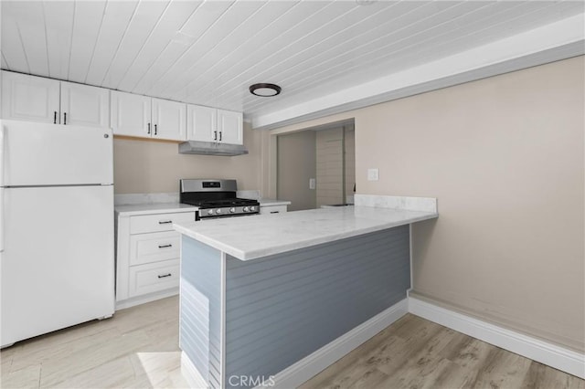 540 Avalon St, Morro Bay, CA 93442 - kitchen with freestanding refrigerator, stainless steel gas range oven, under cabinet range hood, white cabinets, and light wood-style floors