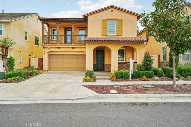 mediterranean / spanish home featuring a balcony, stucco siding, a tile roof, and concrete driveway