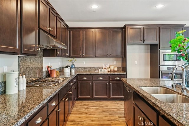 kitchen with a sink, appliances with stainless steel finishes, under cabinet range hood, light wood-style floors, and recessed lighting