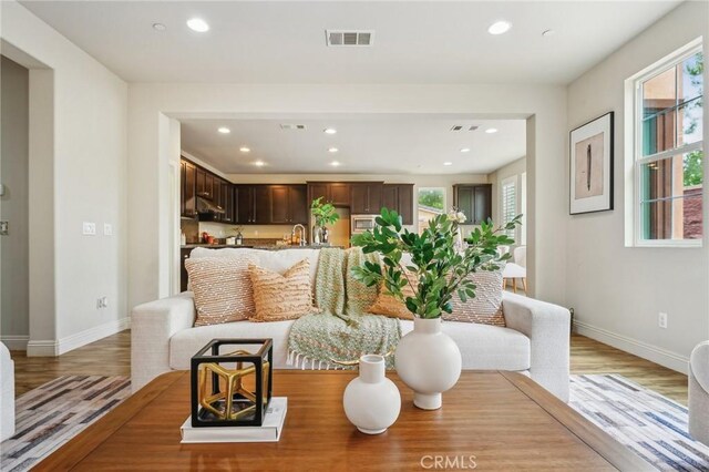 living room featuring recessed lighting, healthy amount of natural light, light wood-style flooring, and baseboards