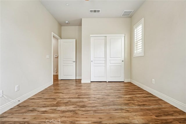 unfurnished bedroom featuring wood finished floors, a closet, and baseboards