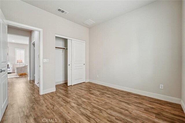 unfurnished bedroom with wood finished floors, baseboards, and a closet