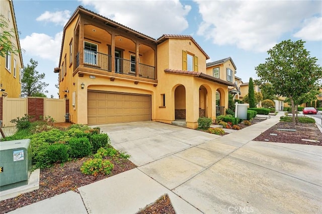mediterranean / spanish house featuring a balcony, an attached garage, stucco siding, a tile roof, and concrete driveway