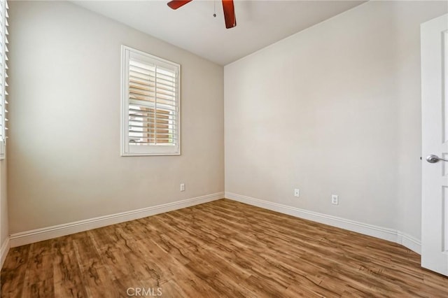 unfurnished room with ceiling fan, wood finished floors, and baseboards
