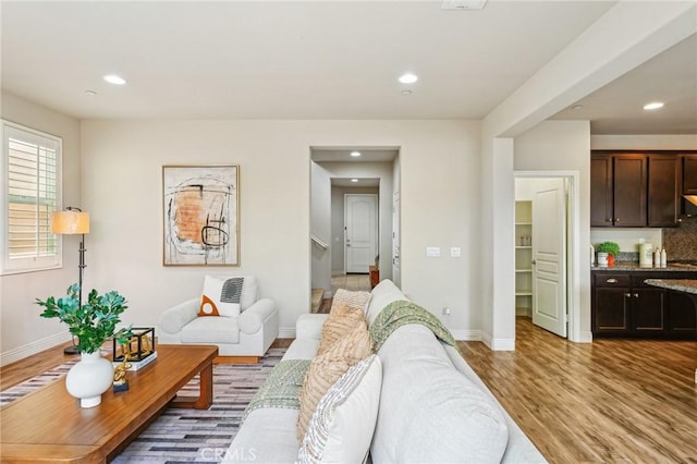 living room with light wood-type flooring, recessed lighting, and baseboards