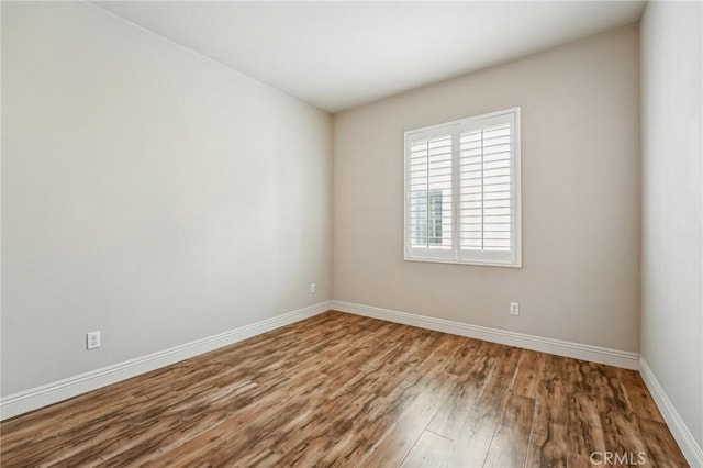 spare room featuring wood finished floors and baseboards