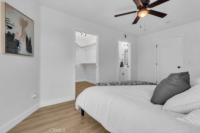 bedroom featuring baseboards, a walk in closet, light wood-style flooring, and a closet