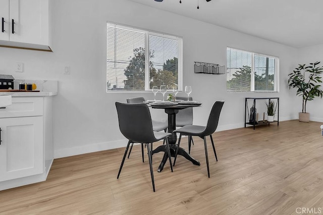 dining room featuring light wood-style floors, baseboards, and a ceiling fan