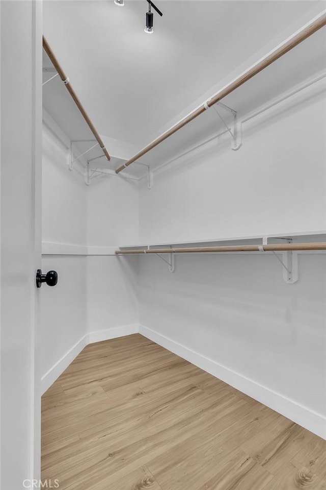 spacious closet with light wood finished floors and attic access