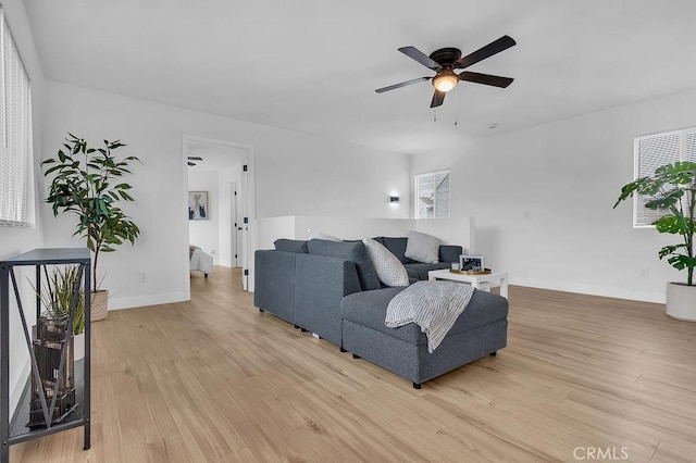 living room featuring light wood-style floors, a ceiling fan, and baseboards
