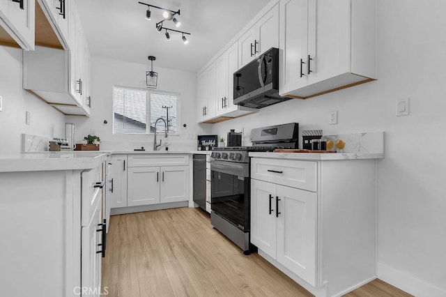 kitchen with stainless steel appliances, a sink, light wood-type flooring, and white cabinets
