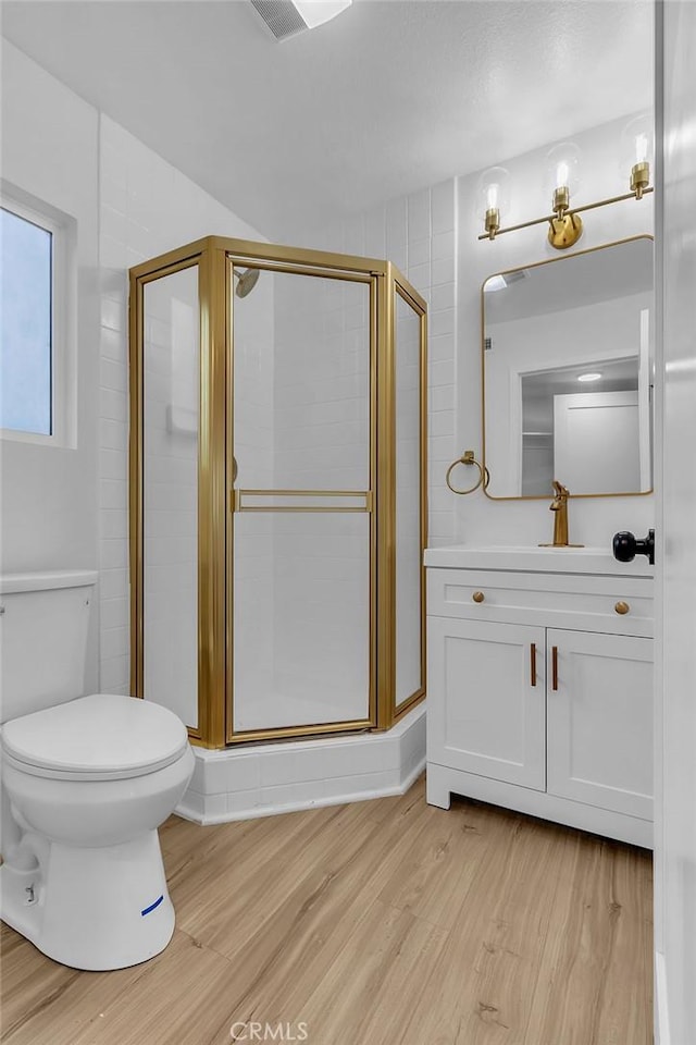 bathroom with wood finished floors, a shower stall, toilet, and vanity