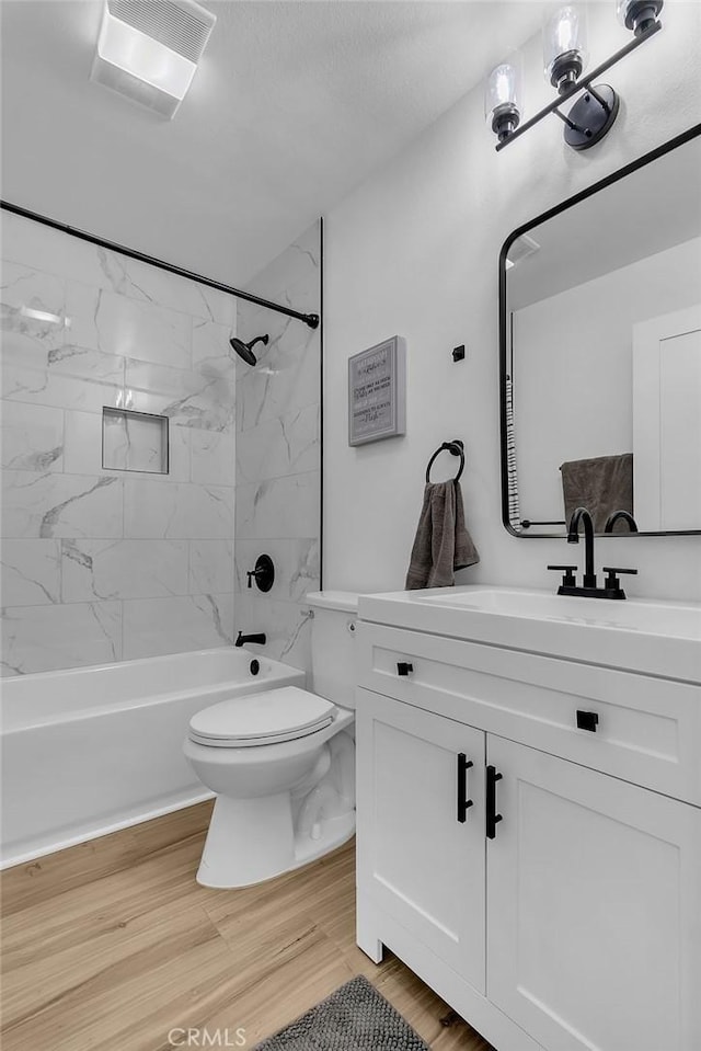 bathroom featuring toilet, vanity, washtub / shower combination, and wood finished floors