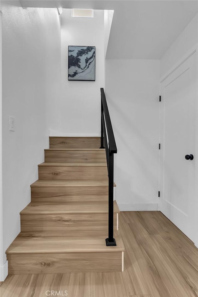 stairs with wood finished floors and baseboards