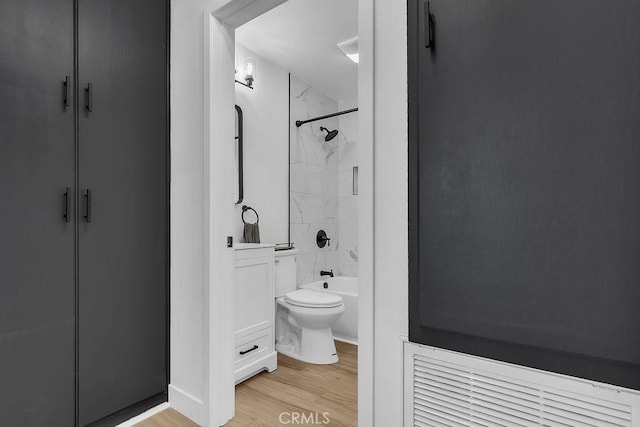 bathroom featuring wood finished floors, toilet, and bathtub / shower combination
