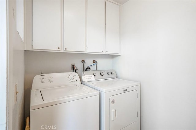 clothes washing area with cabinet space and washing machine and dryer