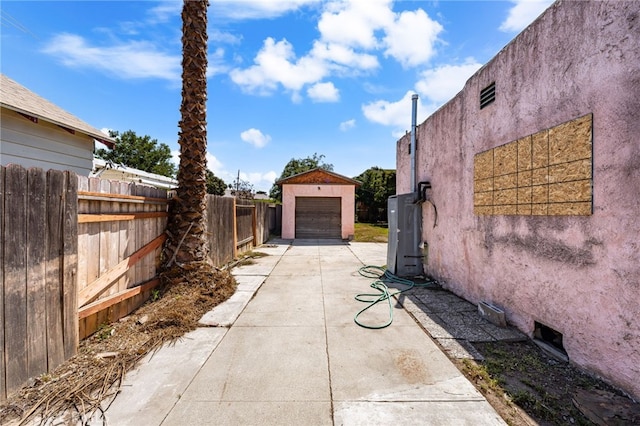view of property exterior featuring stucco siding, fence, driveway, an outbuilding, and a garage