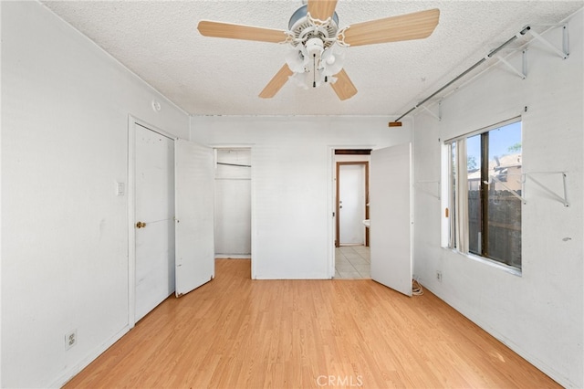 unfurnished bedroom with a textured ceiling, light wood-type flooring, and ceiling fan