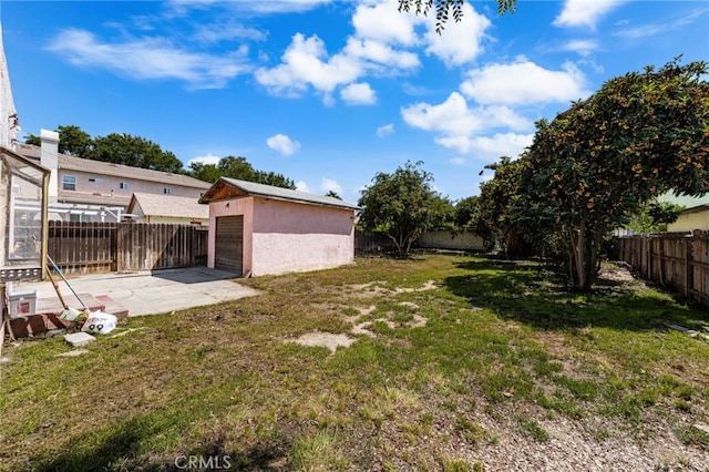 view of yard featuring an outbuilding, a patio area, concrete driveway, and a garage