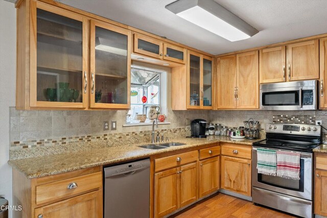 1037 Cortina Ct, Orland, CA 95963 - kitchen with appliances with stainless steel finishes, a sink, light stone countertops, tasteful backsplash, and light wood-style floors