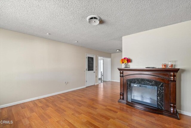 1037 Cortina Ct, Orland, CA 95963 - unfurnished living room featuring wood finished floors, a fireplace, baseboards, and a textured ceiling