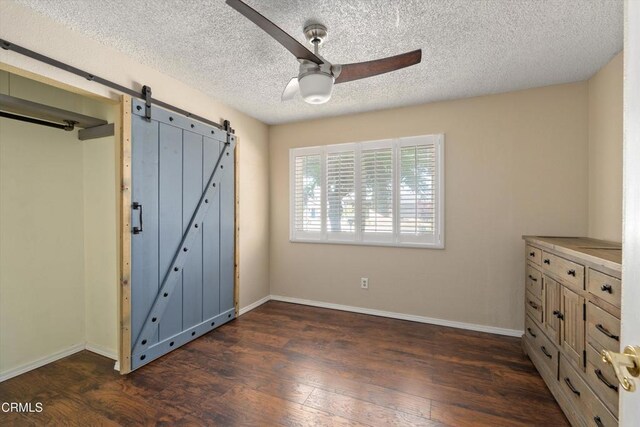 1037 Cortina Ct, Orland, CA 95963 - unfurnished bedroom featuring a barn door, dark wood finished floors, baseboards, a textured ceiling, and a ceiling fan