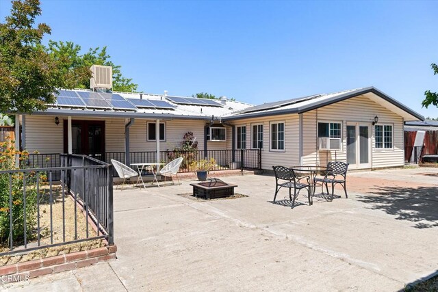 1037 Cortina Ct, Orland, CA 95963 - back of property featuring an outdoor fire pit, roof mounted solar panels, metal roof, cooling unit, and a patio