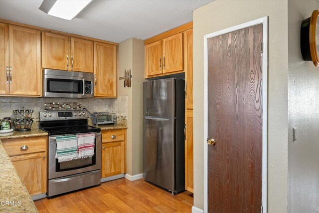 1037 Cortina Ct, Orland, CA 95963 - kitchen featuring stainless steel appliances, light wood-style floors, tasteful backsplash, and light stone countertops