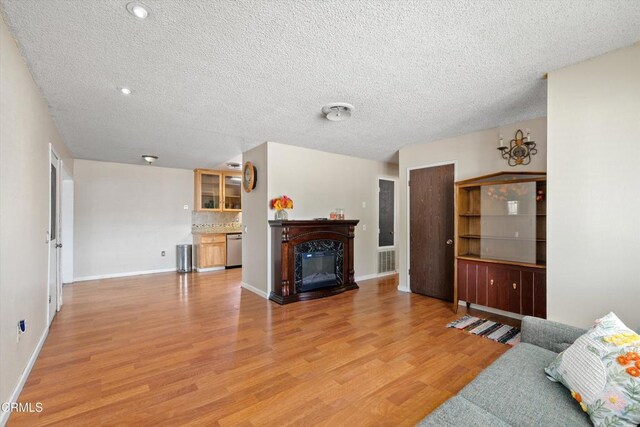 1037 Cortina Ct, Orland, CA 95963 - living area with light wood-style floors, a textured ceiling, baseboards, and a glass covered fireplace