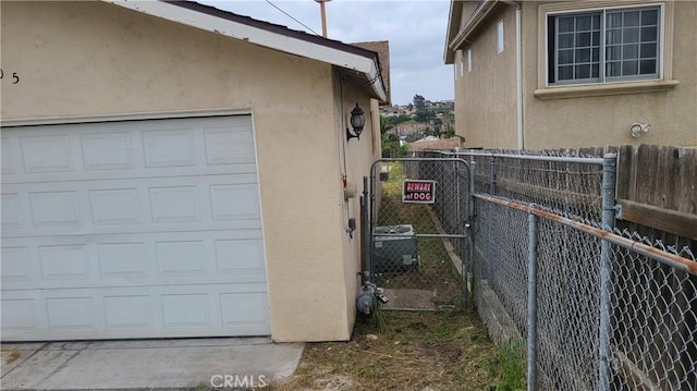 view of home's exterior featuring stucco siding, fence, a garage, and a gate