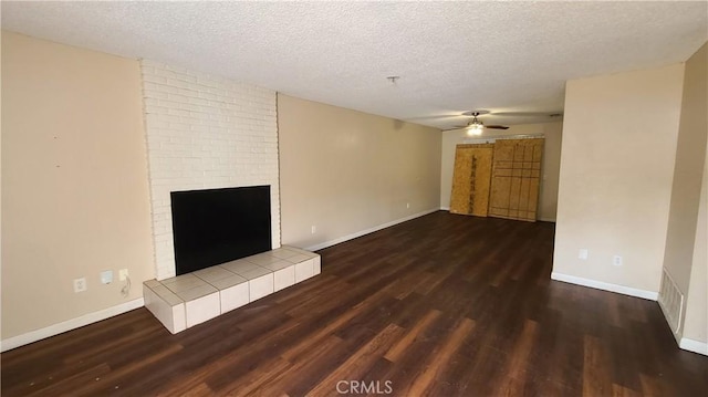unfurnished living room with wood finished floors, a ceiling fan, a textured ceiling, a brick fireplace, and baseboards