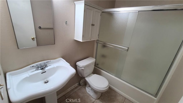 full bathroom with a sink, toilet, tile patterned flooring, and enclosed tub / shower combo