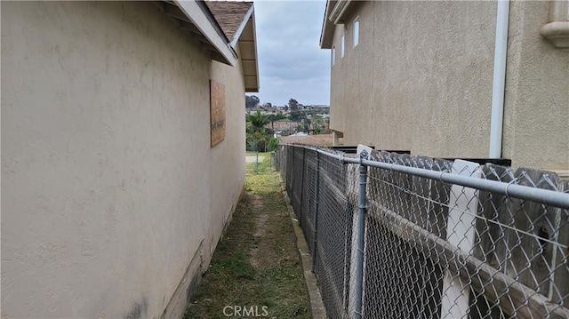 view of side of home with stucco siding and fence