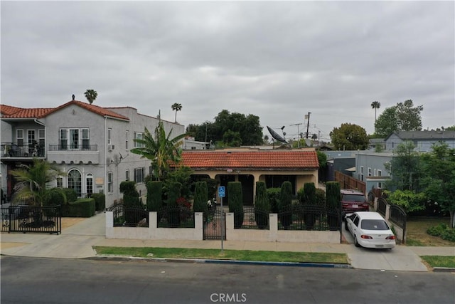view of front facade featuring a tiled roof, a fenced front yard, a gate, and stucco siding
