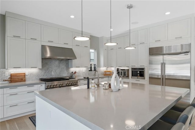 kitchen with extractor fan, a breakfast bar area, white cabinets, and recessed lighting