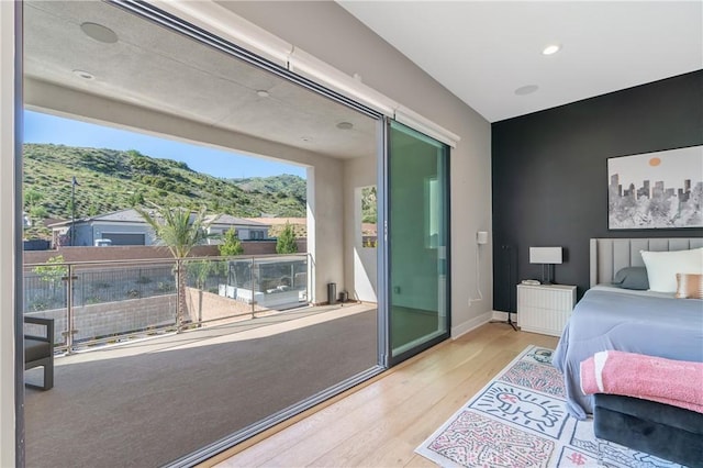 bedroom with wood finished floors, a mountain view, recessed lighting, and baseboards