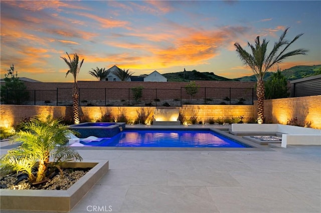 view of pool featuring a patio area, a fenced backyard, and a pool with connected hot tub