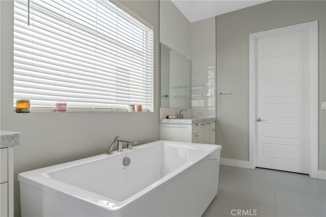 full bathroom with vanity, tile patterned flooring, a freestanding tub, and baseboards