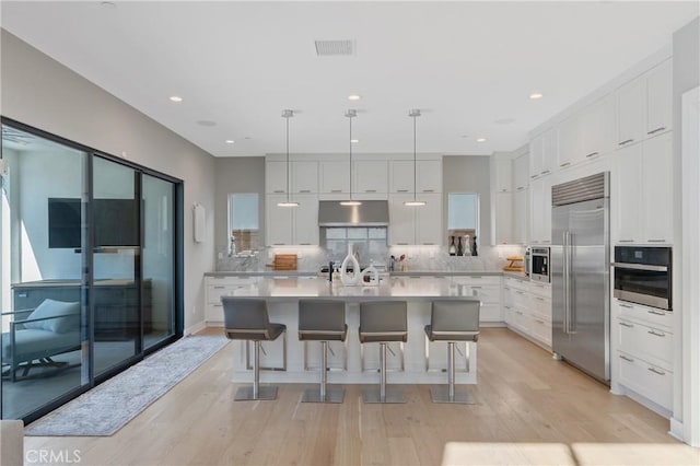kitchen with appliances with stainless steel finishes, under cabinet range hood, light wood-style flooring, white cabinetry, and recessed lighting