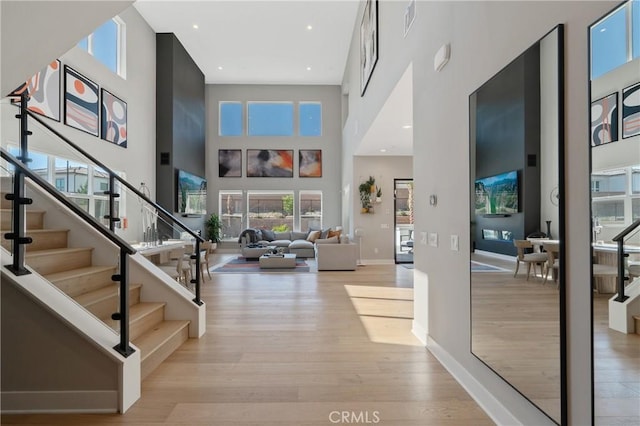 entrance foyer featuring wood finished floors, a high ceiling, stairs, plenty of natural light, and baseboards